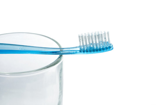 Blue tooth brush lies on a glass on white