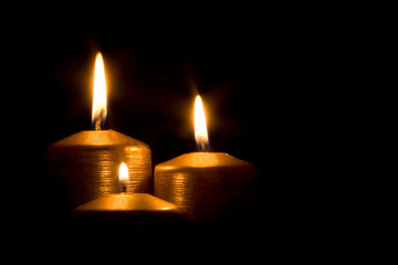 Three golden candles burning in the darkness