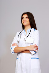 Beautiful young happy doctor over grey background