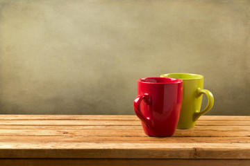 Coffee cups on wooden table over grunge background