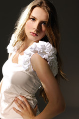 Portrait of pretty young woman in white clothing on black