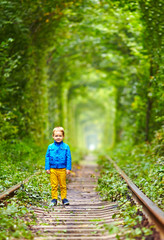 Naklejka na ściany i meble smiling kid walking the rails in green tonel
