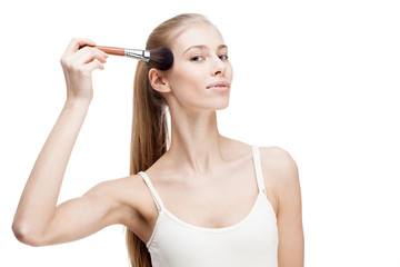 young blond woman holding cosmetics brush on white