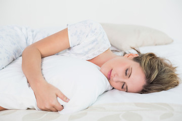 Obraz na płótnie Canvas Peaceful woman lying on bed embracing pillow