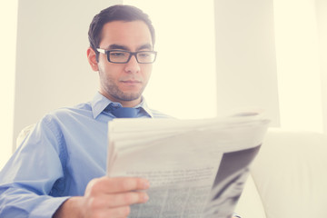 Unsmiling man reading a newspaper