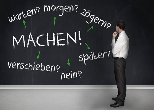 Thoughtful businessman looking at words machen warten morgen zog