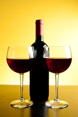 two red wine glasses near bottle