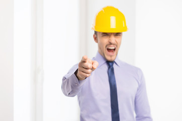 Angry architect. Furious architect in hardhat pointing camera an