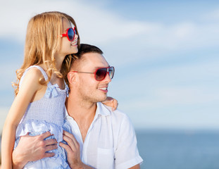 happy father and child in sunglasses over blue sky