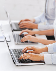 group of people working with laptops in office