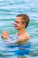 teenage boy enjoys swimming in the ocean and laughes