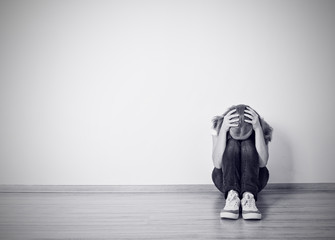 girl sits in a depression on the floor near the wall