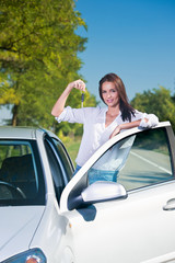 Beautiful woman standing next to a car holding car keys