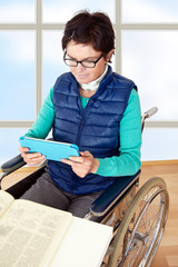 Woman with Tablet PC's in a wheelchair at the table