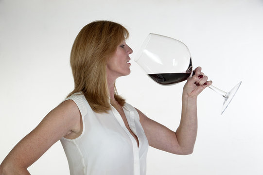 Woman drinking from a very large glass of red wine