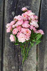 small pink garden roses on wooden surface