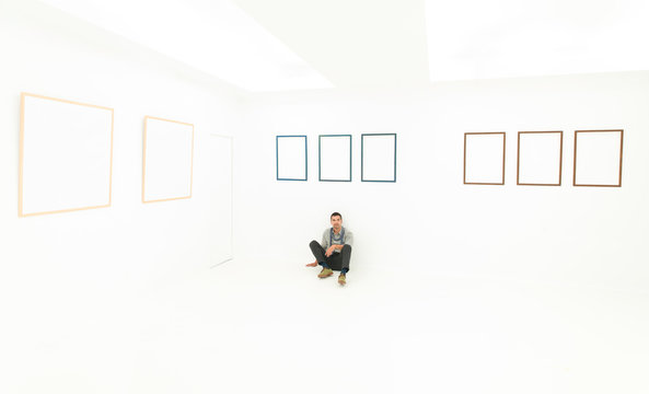 relaxed man sitting on a floor in art gallery