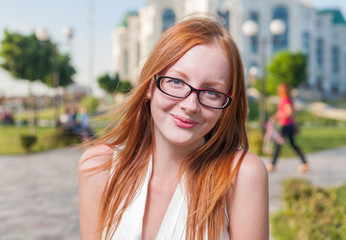 Beautiful 20s aged redhead smiling woman outdoors in glasses