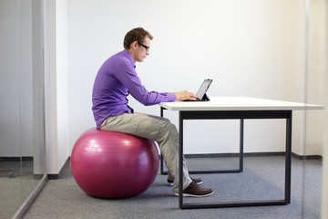 bad sitting posture at desk on stability ball with tablet
