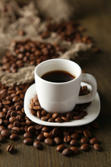 Cup of coffee and coffee beans on wooden background