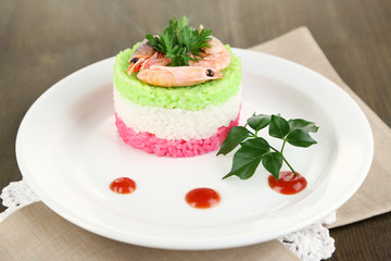Colored rice on plate on napkin on wooden table