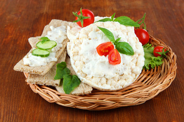 Tasty crispbreads with vegetables on wooden background
