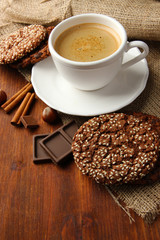 Cup of tasty coffee with tasty cookies, on wooden background