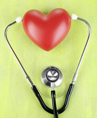 Stethoscope and heart on wooden table close-up