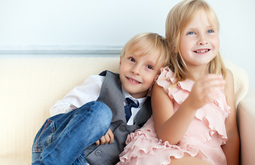 Brother and sister are sitting on the sofa