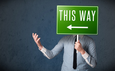 Businessman holding a direction sign