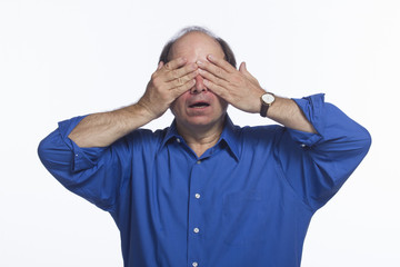 Shocked man covering eyes, horizontal