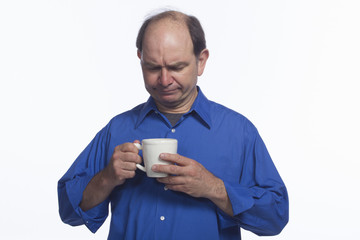 Disappointed man looks down at coffee cup, horizontal