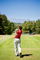 Golf player performs a tee shot