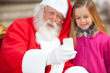 Santa Claus And Girl Taking Selfportrait Through Smartphone