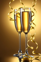 glasses of champagne and streamer on yellow background