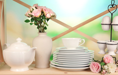 Lots beautiful dishes on wooden shelf on natural background