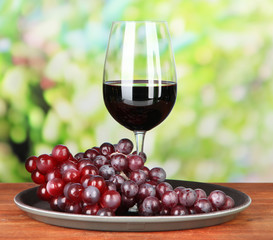 Ripe grapes and glass of wine, on bright background