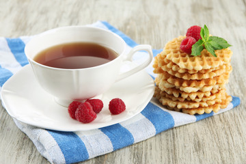 Cup of tea with cookies and raspberries on table close-up