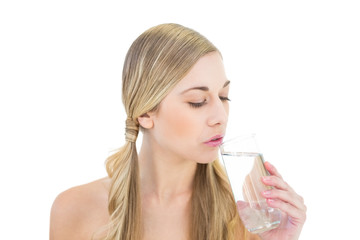 Stern young blonde woman drinking water
