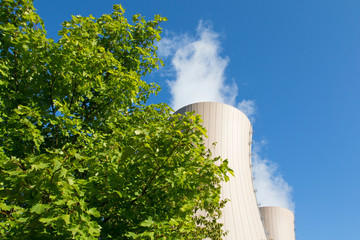 Green tree branches against a nuclear power plant