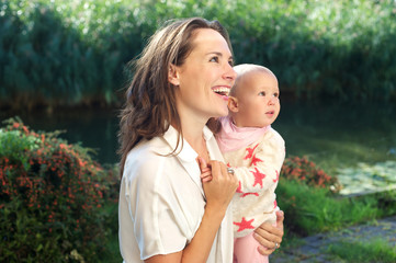Portrait of a happy mother smiling with cute baby outdoors