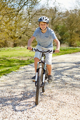 Fototapeta premium Young Boy Riding Bike Along Country Track