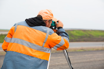 Industrial worker making measuring with theodolite