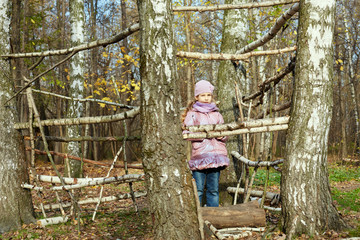 Naklejka na ściany i meble Little girl stands in autumn park inside frame made of live tree