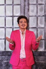 Smiling young man in pink suit stands against old icy door