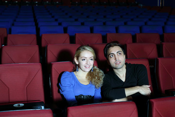 Young man and woman watch movie in movie theater. Focus on girl.