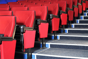 Rows of red seats and stairs in auditorium in cinema theater - obrazy, fototapety, plakaty