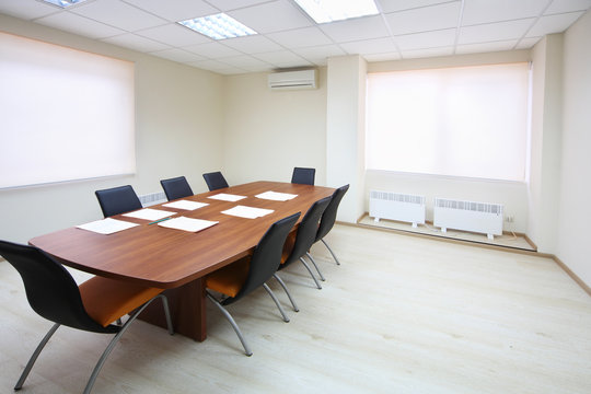 Empty lighting meeting room with long table with papers