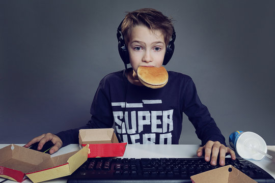 enfant mangeant hamburger devant ordinateur