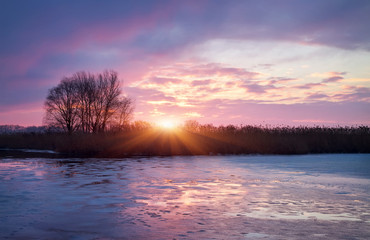 Fototapeta na wymiar Winter landscape with sunrise sun and frozen river.